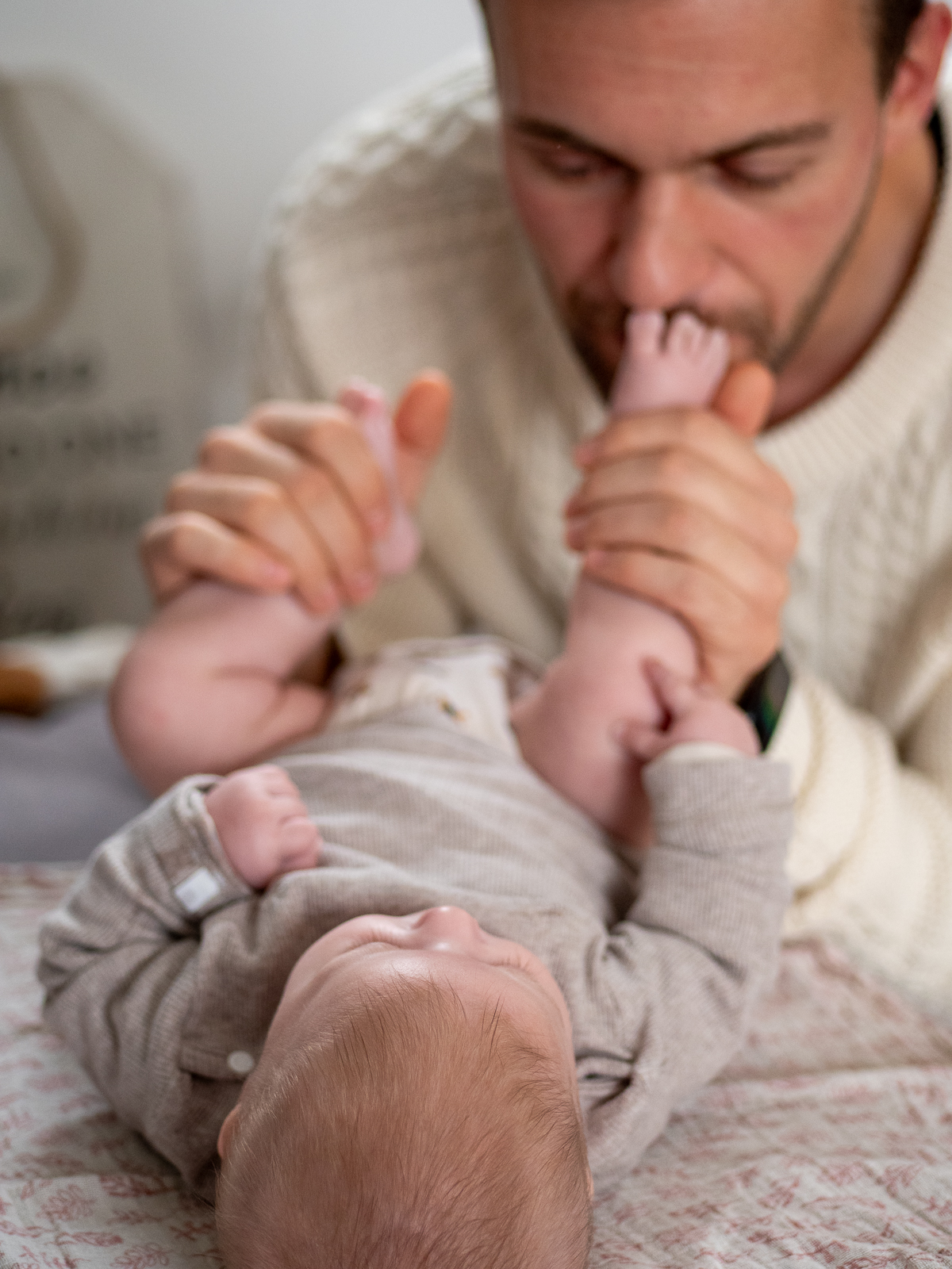 Vater küsst zärtlich die Babyfüße bei einem emotionalen Familienshooting im Wohnzimmer in Bonn