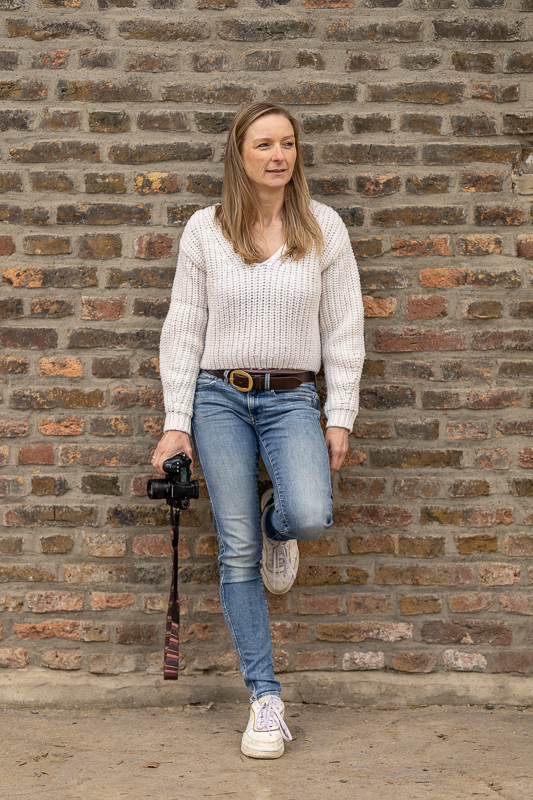 Fotografin aus Bonn mit Kamera schaut aufmerksam in die Ferne bei einem authentischen Portrait