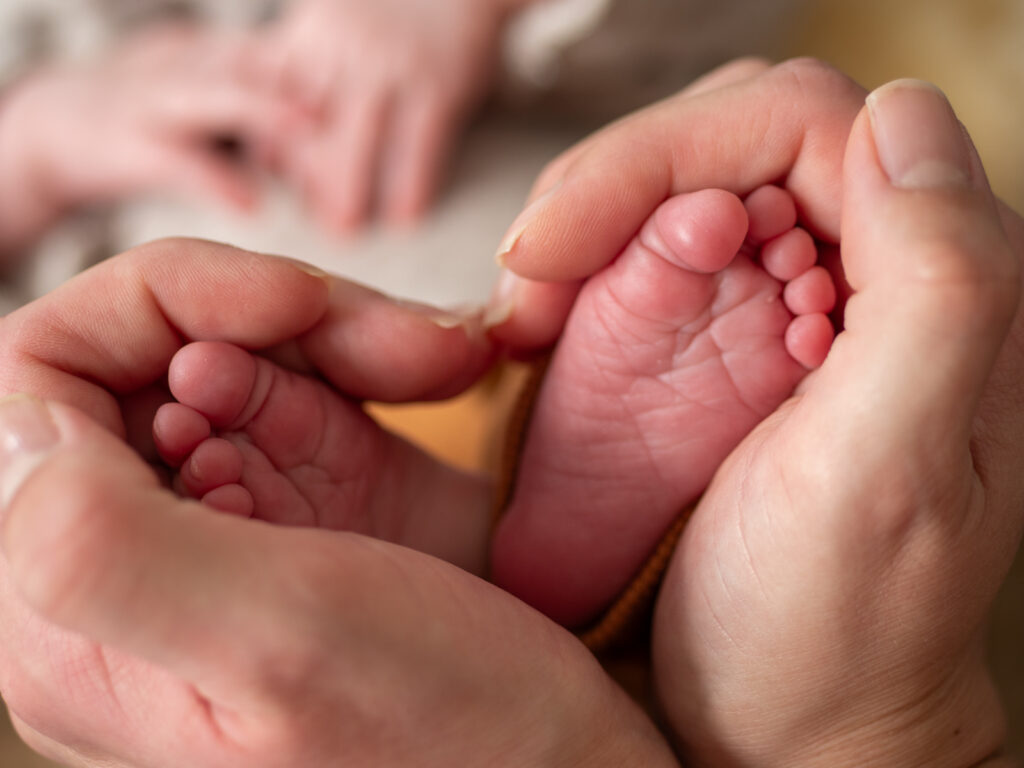 Babyfüße umrahmt von Mamas Händen beim Newborn Shooting in Bonn