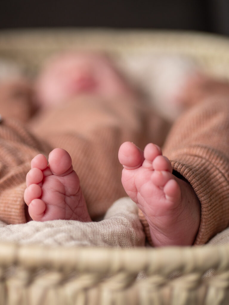 Neugeborenen Detailfoto mit Fokus auf Füße und unscharfem Baby im Hintergrund in Bonn