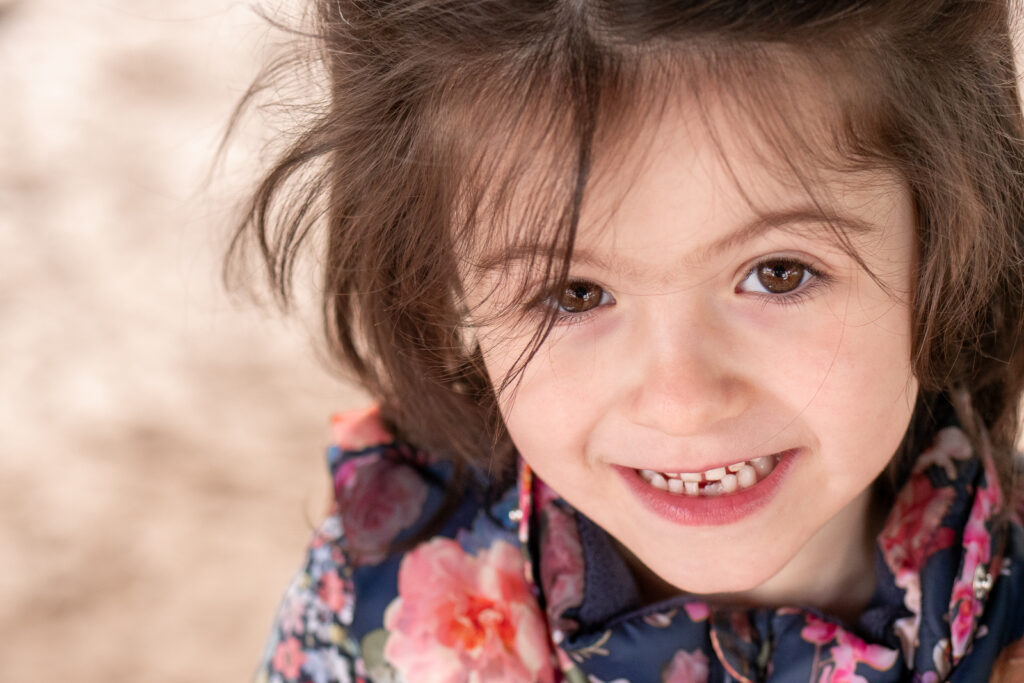 Natürliches Kinderportait, auf dem ein Mädchen aufmerksam direkt in die Kamera schaut.